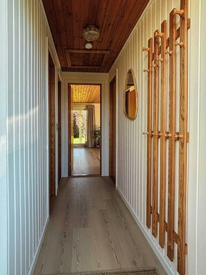 Ein Korridor mit Holzboden, weißen Wänden und einer Holzkονstruktion an der Decke.