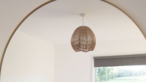A bedroom with a bed, a window, a radiator, and a hanging light fixture.