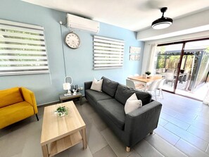 A modern living room with a sofa, a yellow armchair, a coffee table, and a dining area with a table and chairs. - Charming Villa | Pool & Jacuzzi Near Beaches (Bavaro, Punta Cana)