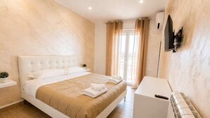 A hotel room with a bed, a TV, a desk, and a window with curtains. - Vacation House Grecale Apartment Leonardo Airport (Isola Sacra)