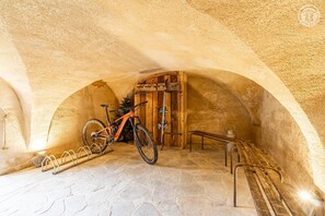 Una estança de pedra amb arc, una bicicleta, una porta de fusta i una banca.