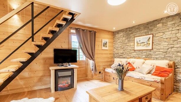 Een houten interieur met een trap, een open haard, een bank en een televisie.