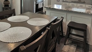 A modern kitchen with a central island, built-in appliances, and a dining area with placemats.