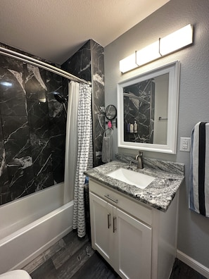 Une salle de bain avec une douche en marbre, un lavabo dotĂ© dâun plan de travail en granit et un miroir au-dessus du lavabo.