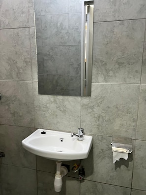 Ein Badezimmer mit einem weißen Waschbecken, einem Spiegel und gefliesten Wänden.