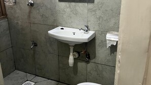 Ein Badezimmer mit einem weißen Waschbecken, einer Toilette und einer Duschkabine.