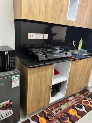 Une cuisine de taille réduite, équipée d’une cuisinière noire, d’un four à micro-ondes et d’un réfrigérateur.