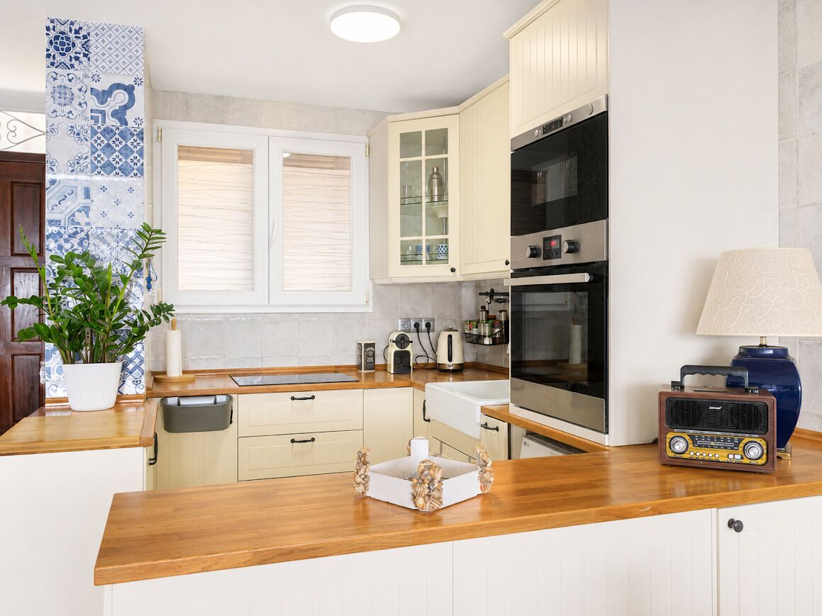 A kitchen with wooden countertops, a sink, cabinets, a stove, and a radio.