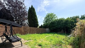 A backyard with a swing set, a wooden fence, and a tall tree. -  Semi-Detached w/Pool Table & Garden (Cardiff)