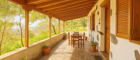 Une terrasse couverte avec un sol en pierre, des meubles en bois et des plantes en pot.