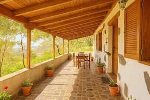 Un patio cubierto con suelo de piedra, muebles de madera y plantas en macetas.