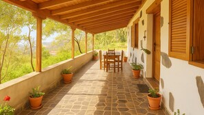 A covered patio with a stone floor, wooden furniture, and potted plants. - Casa Ramón, rural retreat by Garajonay Park (Agulo)