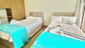 Habitación de hotel con dos camas, un armario de madera y una ventana con cortinas.