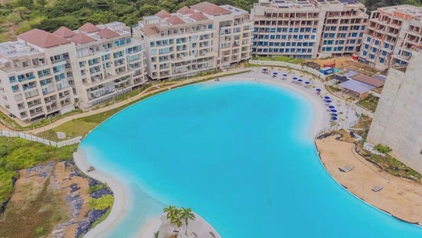 Una gran piscina curvada rodeada de edificios de hotel de varios pisos.