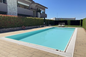 A rectangular swimming pool with a white safety border, a stone wall, and a hedge. - 20 min from Gardaland and lake with swimming pool (Valeggio sul Mincio)
