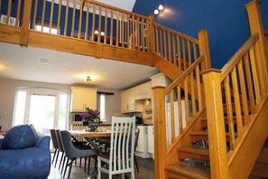 Eine moderne Küche mit weißen Schränken, ein Essbereich mit Tisch und Stühlen sowie eine Holztreppe.