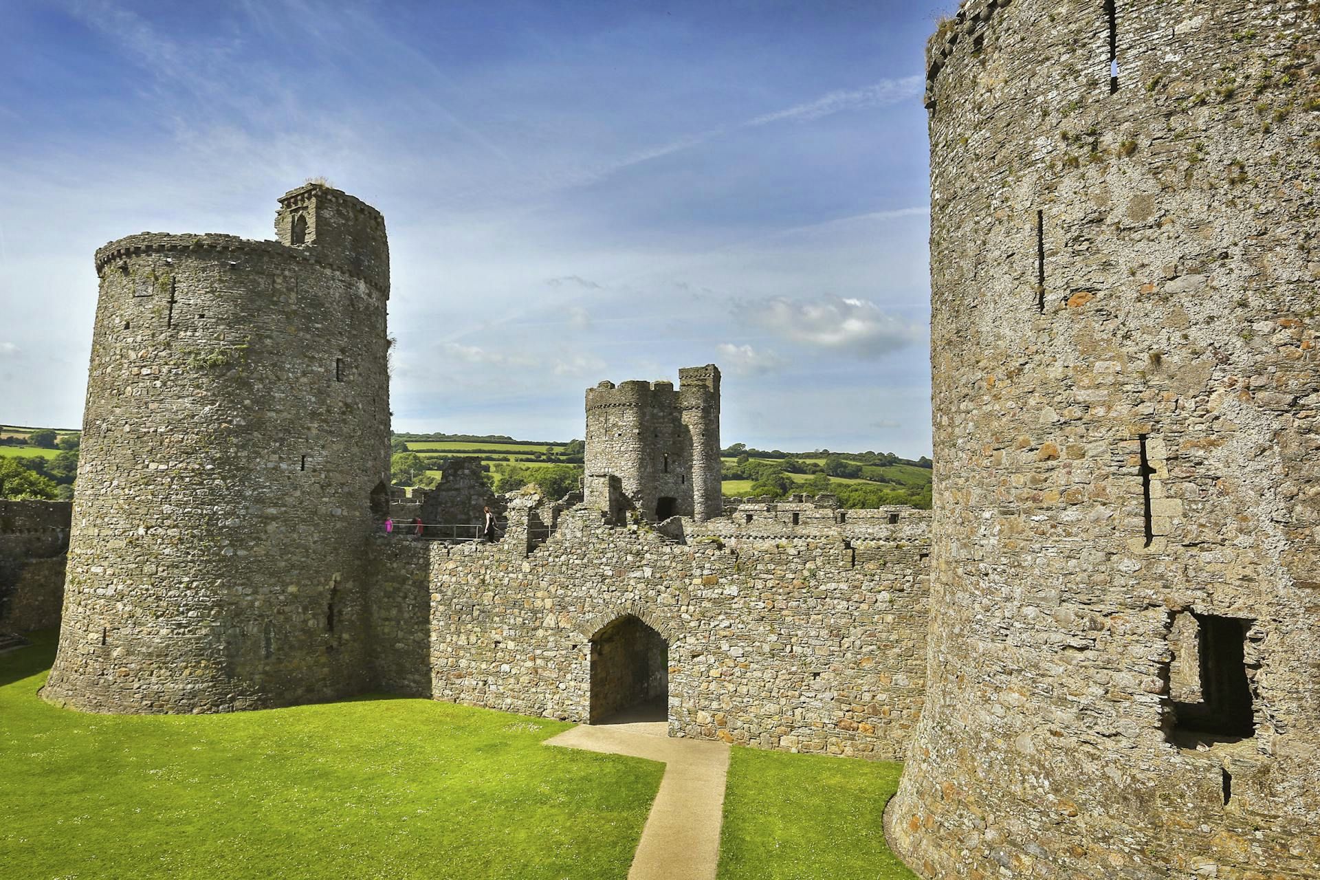 A historic stone castle with multiple towers and a well-maintained lawn.
