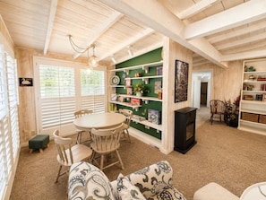 Ein gemütliches Zimmer mit rundem Tisch, Stühlen, einem Bücherregal und einem Kamin.