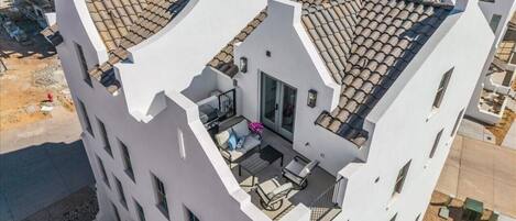 A multi-story building with a rooftop terrace, balconies, and a modern architectural style.