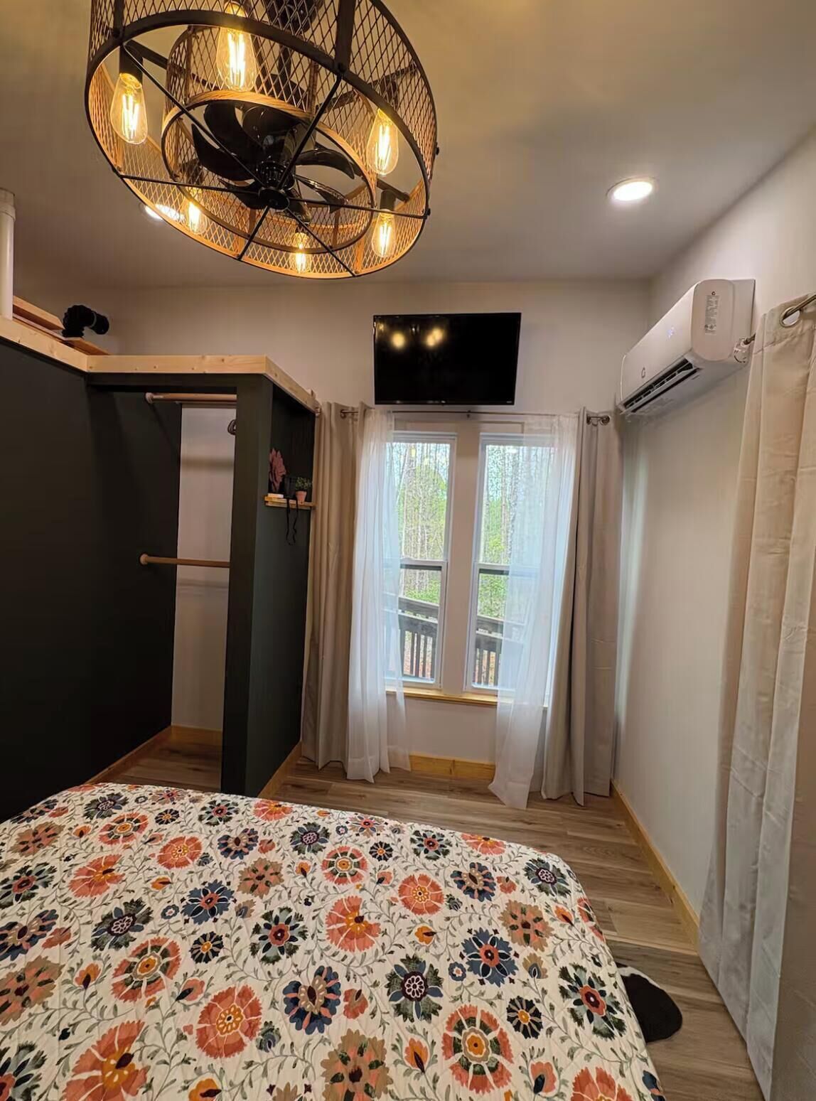 Ein Schlafzimmer mit Bett, Deckenventilator, Fernseher und Klimaanlage.