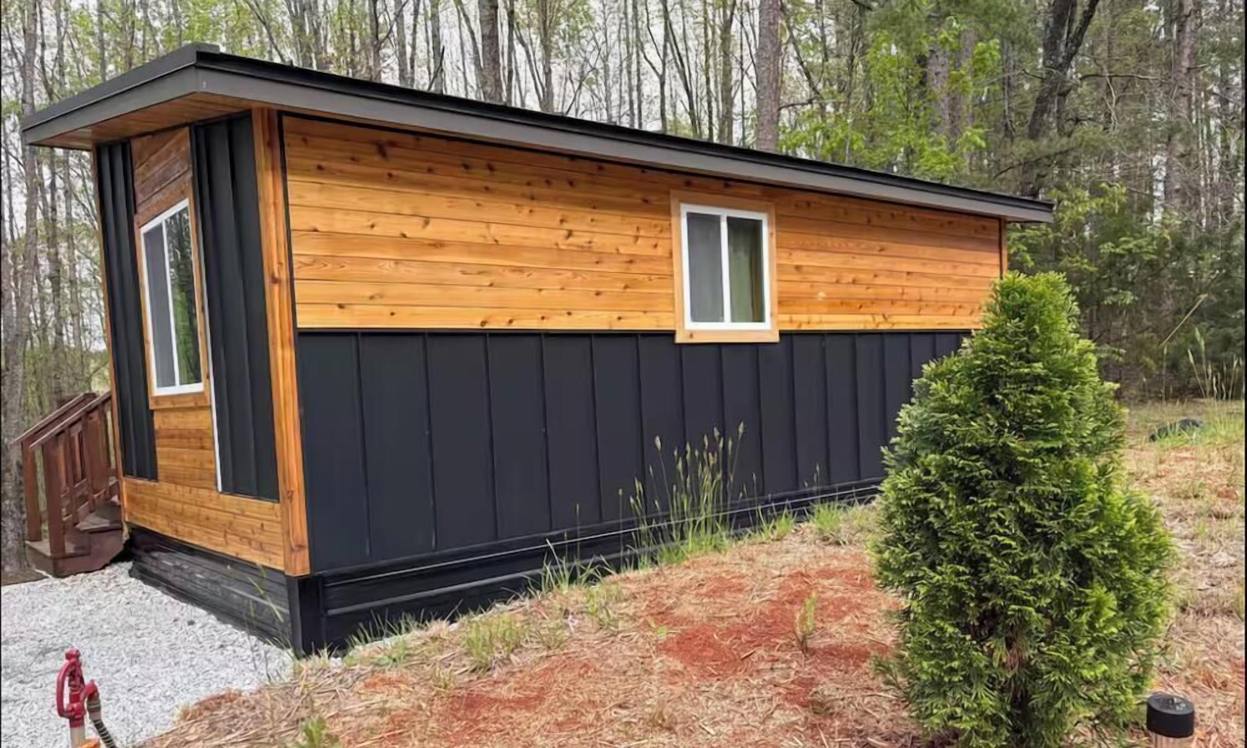 A small cabin with a wooden exterior, a black door, and a window.