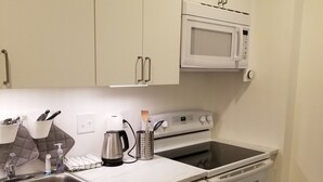 A compact kitchen with white cabinets, a microwave, a stove, and a dishwasher. - Cozy 1-bedroom apartment in  Bethesda (Bethesda)