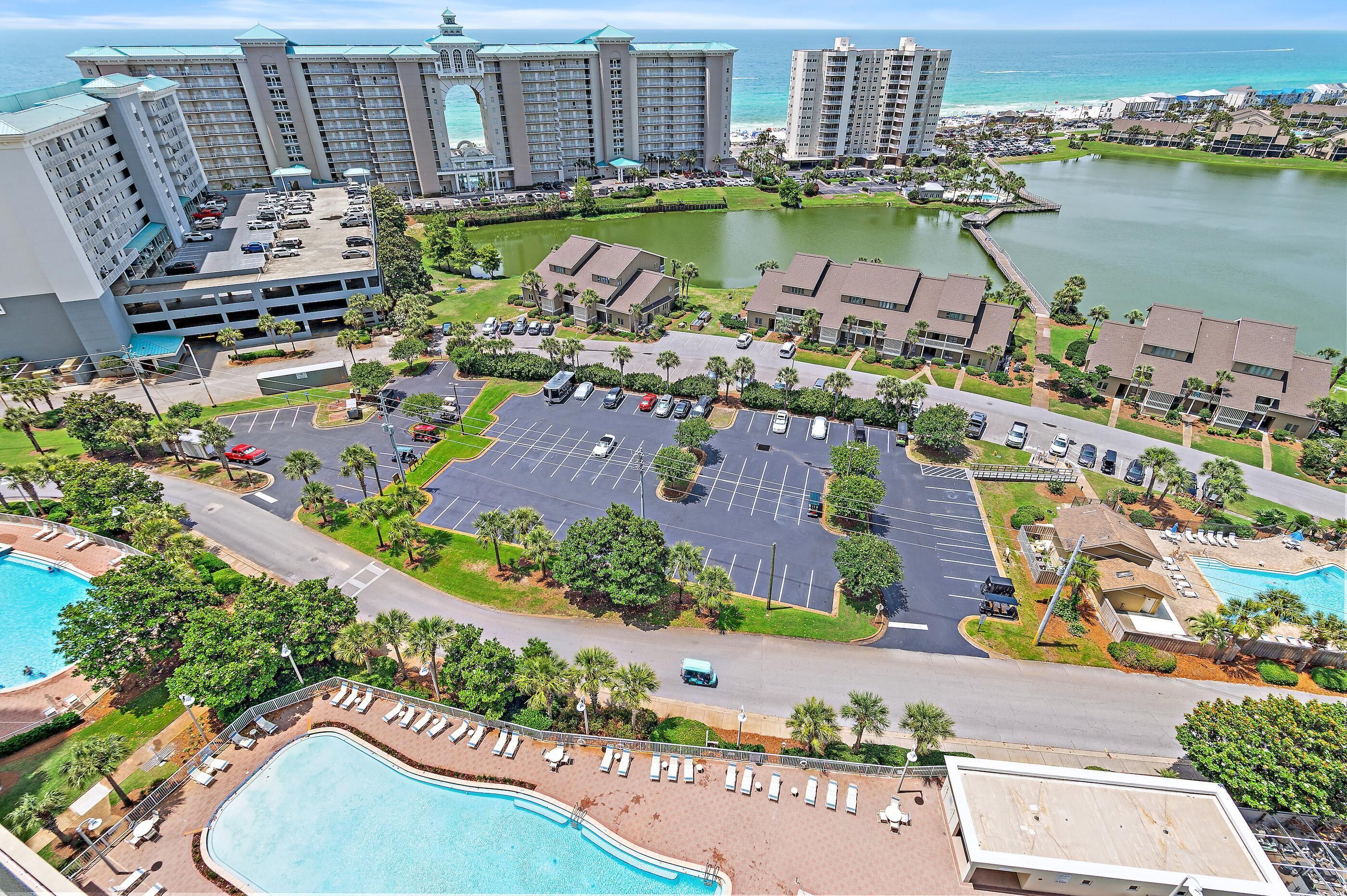 A resort with a large parking area, swimming pools, and a view of the ocean.