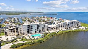 Un hotel frente al mar con varias construcciones, piscina y puerto deportivo.