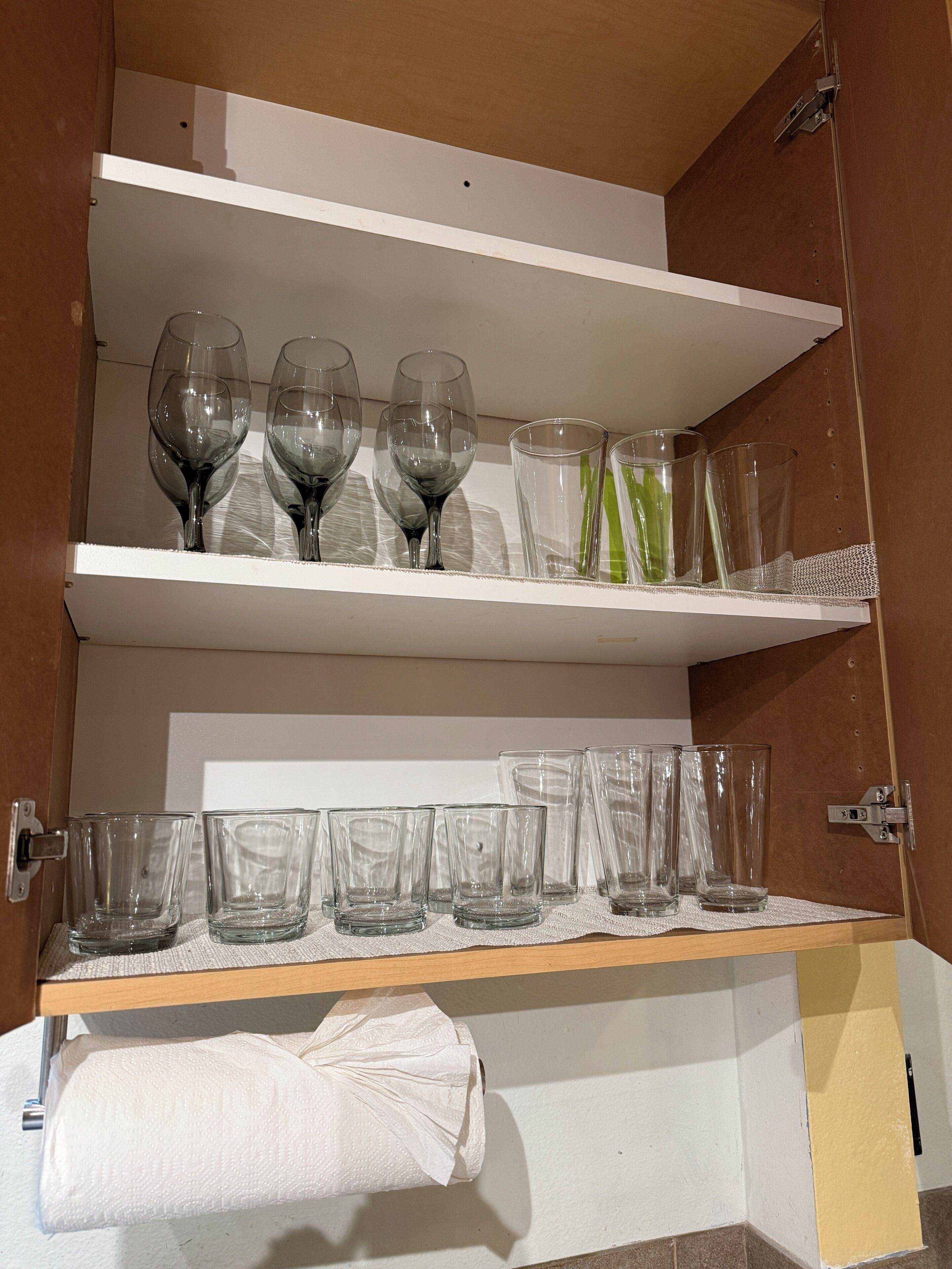 Un meuble de rangement doté d’étagères où sont rangés divers articles en verre, notamment des verres à vin et des verres à cocktail.