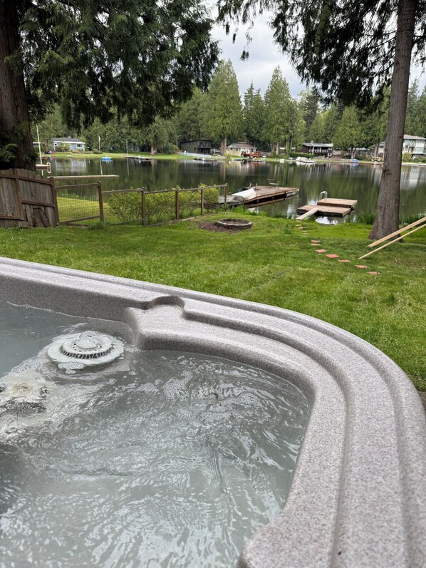 En swimmingpool med en kant av sten, omgiven av en gräsyta och ett trädäck.