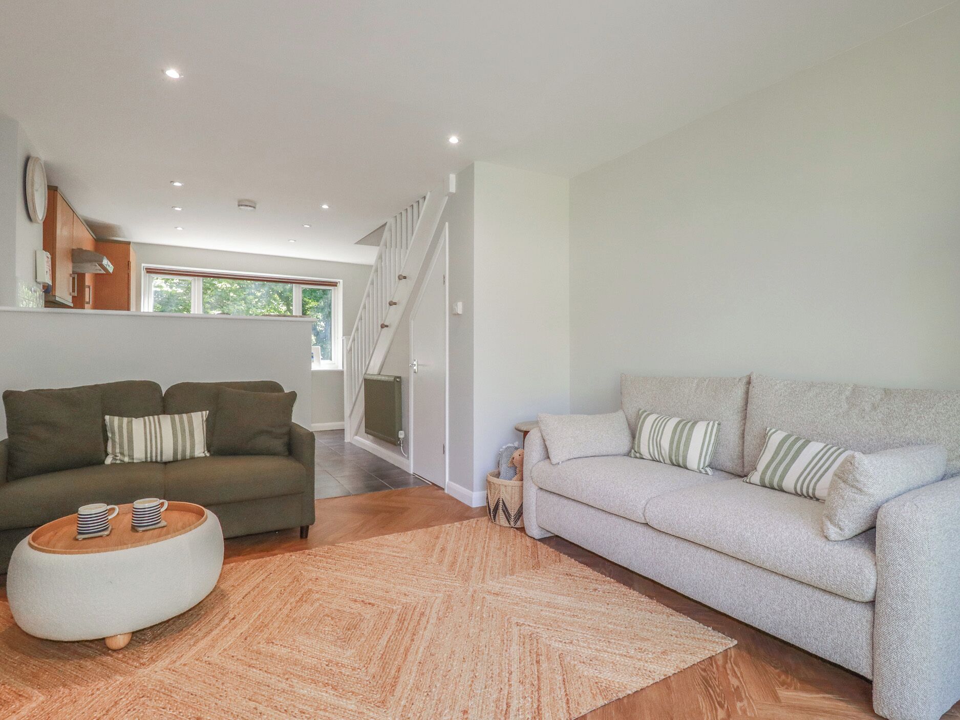 A modern living room with two sofas, a coffee table, and a staircase.