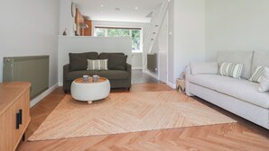 A modern living room with a sofa, a coffee table, and a staircase leading to another room. - 67 Manor Villas (St. Columb Major)
