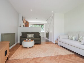 A modern living room with a sofa, a coffee table, and a staircase leading to another room. - 67 Manor Villas (St. Columb Major)