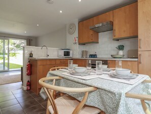 A kitchen with wooden cabinets, a microwave, and a dining table set for four. - 67 Manor Villas (St. Columb Major)