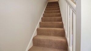 A carpeted staircase with white railings and a plain wall. - 67 Manor Villas (St. Columb Major)
