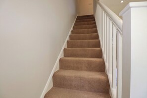 A carpeted staircase with white railings and a plain wall. - 67 Manor Villas (St. Columb Major)
