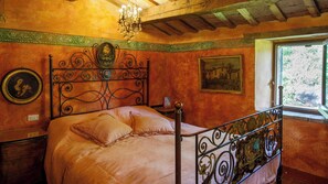 Ein Schlafzimmer mit einem Bett, einer Chandelier, einem Gemälde und einem Fenster.