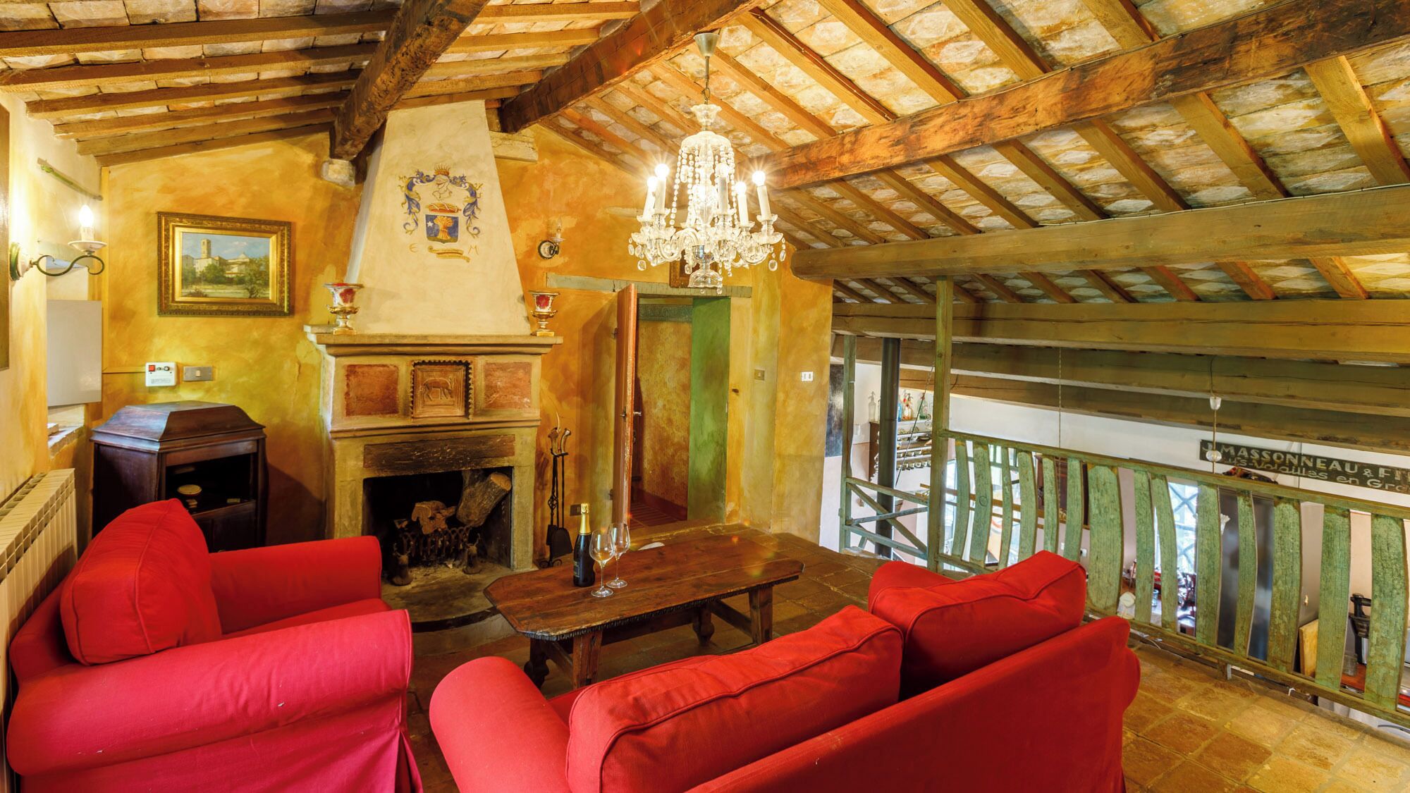 Un interior rústic amb una llar de foc, seients vermells i un penjall.