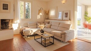 A living room with a sofa, a coffee table, a fireplace, and a view of the outdoors. - Villa Oxa 12+2, Emma Villas (Imola)
