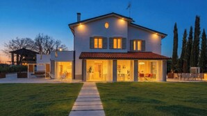 A two-story house with a covered patio, a lawn, and a pathway leading to the entrance. - Villa Oxa 12+2, Emma Villas (Imola)