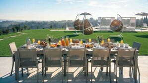 An outdoor dining setup with a table set for breakfast, surrounded by chairs, with a scenic view in the background. - Villa Oxa 12+2, Emma Villas (Imola)