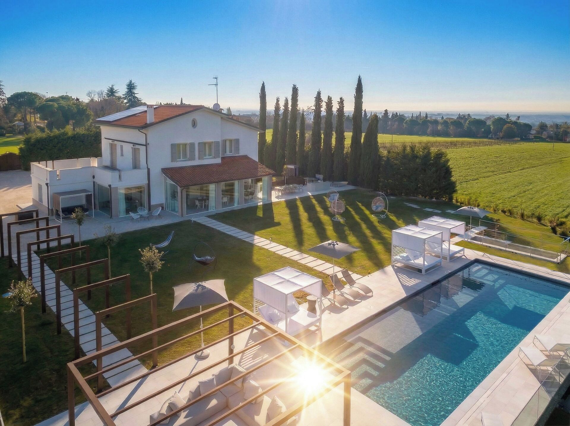 A modern villa with a swimming pool, outdoor seating, and a well-maintained lawn.