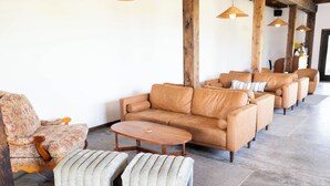Un área de estar con un sofá, sillones, reposapiés y una mesa de centro de madera.