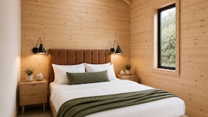 Una habitación con paneles de madera, una cama, mesitas de noche y un ventanal.