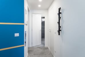 A hallway with a blue wall, a white door, and a black abstract wall art piece. - 8 Min walk from the Station, Designer Studio Flat (Milan)