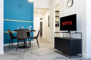 A modern living room with a dining area, a television on a stand, and a clock on the wall. - 8 Min walk from the Station, Designer Studio Flat (Milan)