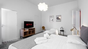 Een moderne hotelkamer met een bed, twee nachtkastjes, een televisie, een stoel en een bureau.