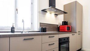 Een moderne keuken met een inbouwoven, een rode magnetron en een raam met uitzicht.