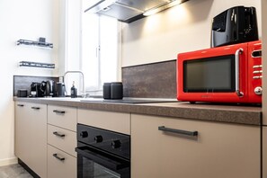 A modern kitchen with a red microwave, black oven, and a coffee machine. - 8 Min walk from the station and Corso Buenos Aires (Milan)