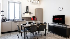 Een moderne keuken met een eethoek, een televisie en een klok aan de muur.